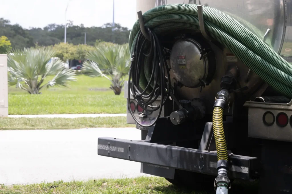 Rear view of a tanker truck with coiled green and black hoses attached.