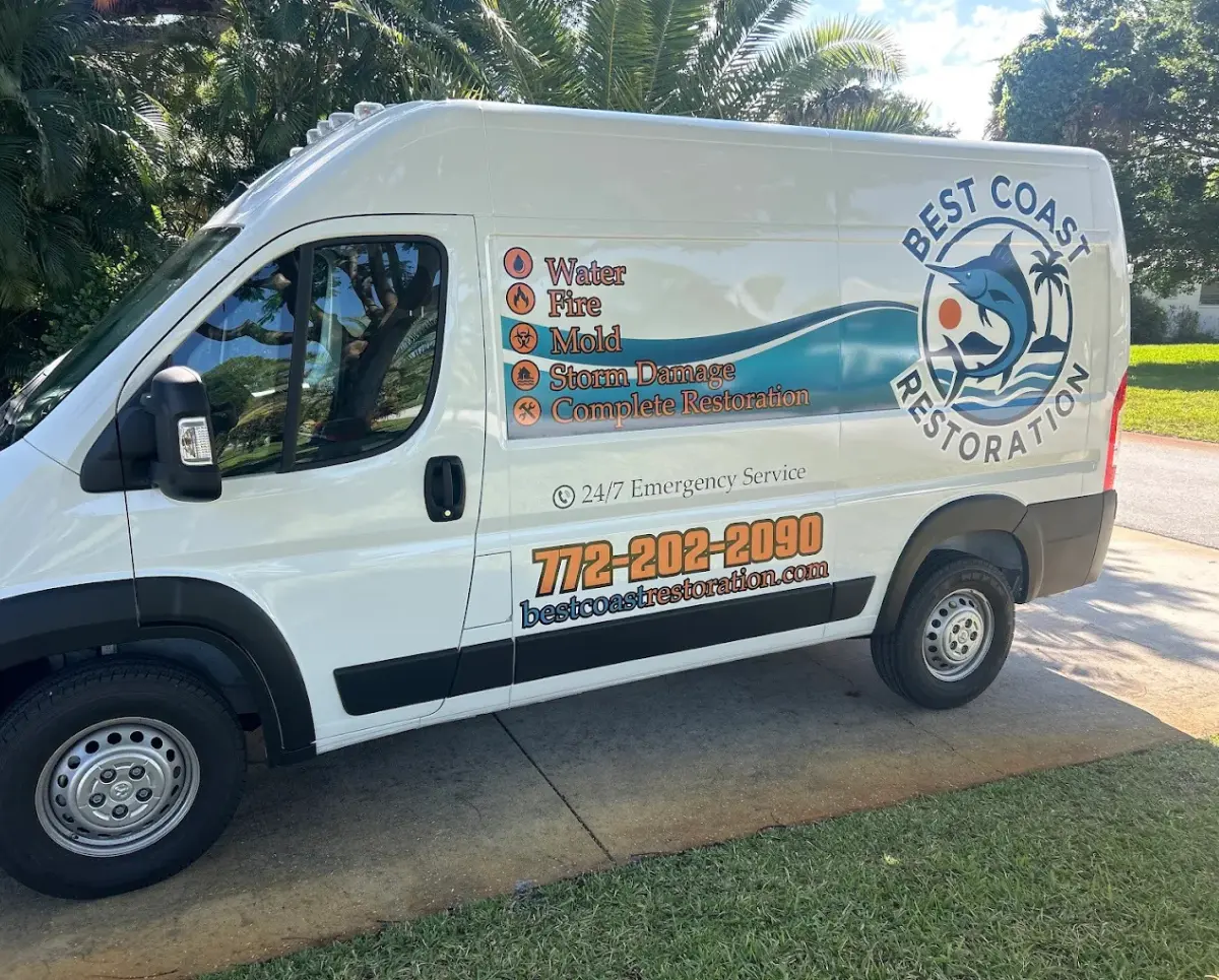 White van with "Best Coast Restoration" logo and services listed, parked on a driveway near grass and trees.